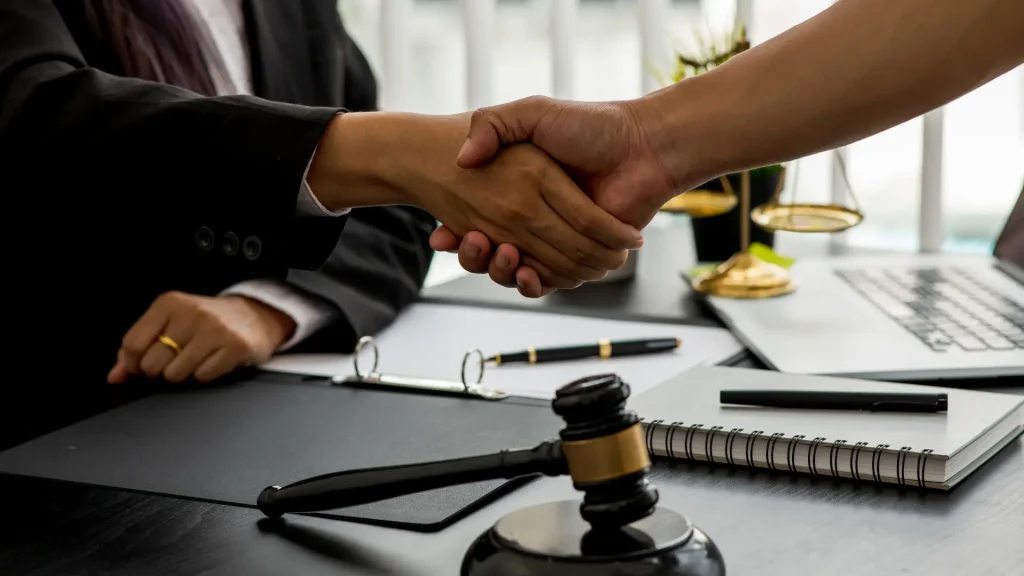 Attorney and client shake hands over gavel, sealing agreement