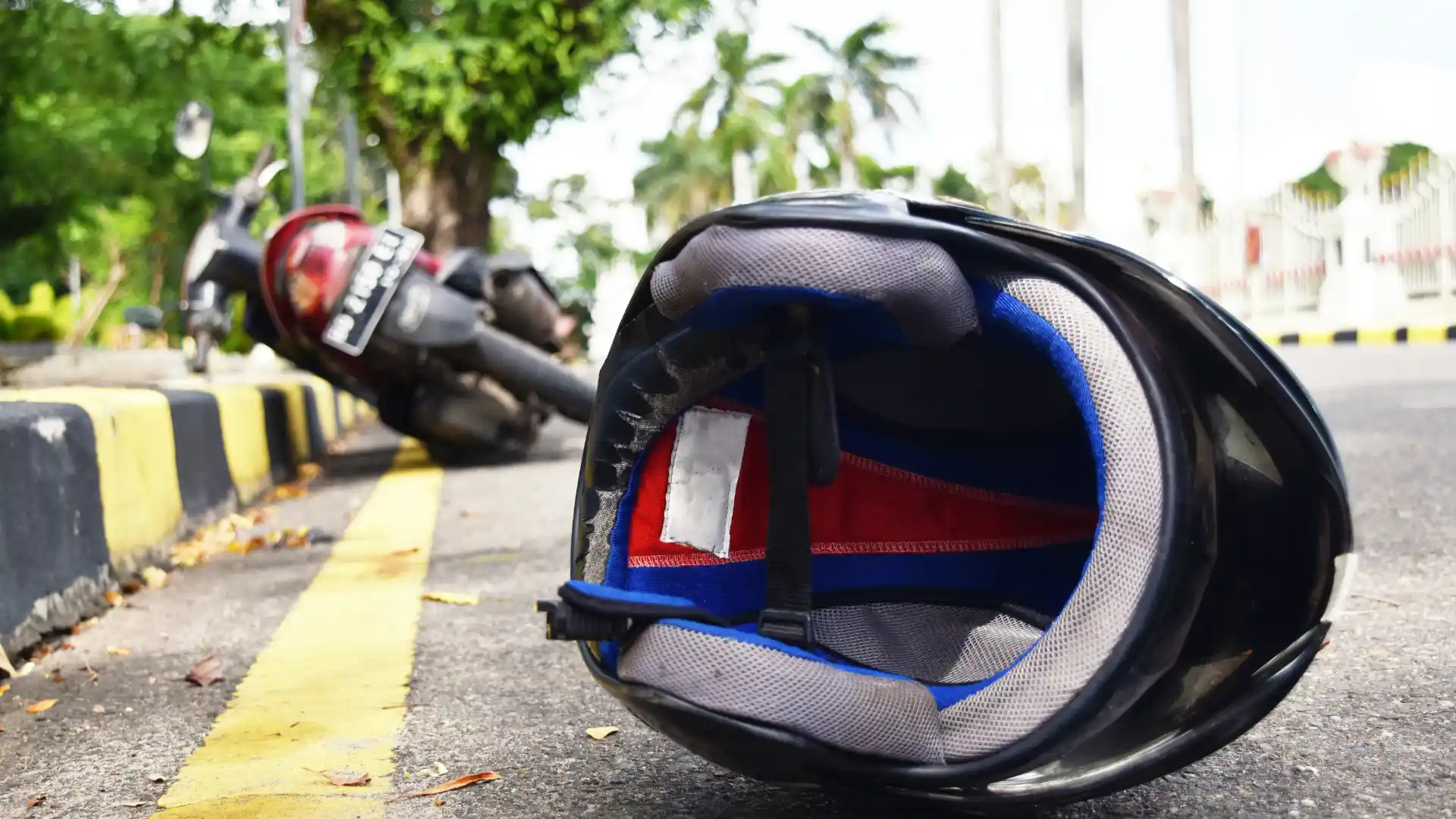 Motorcycle helmet lying on the road near a fallen motorbike, indicating the aftermath of an accident.