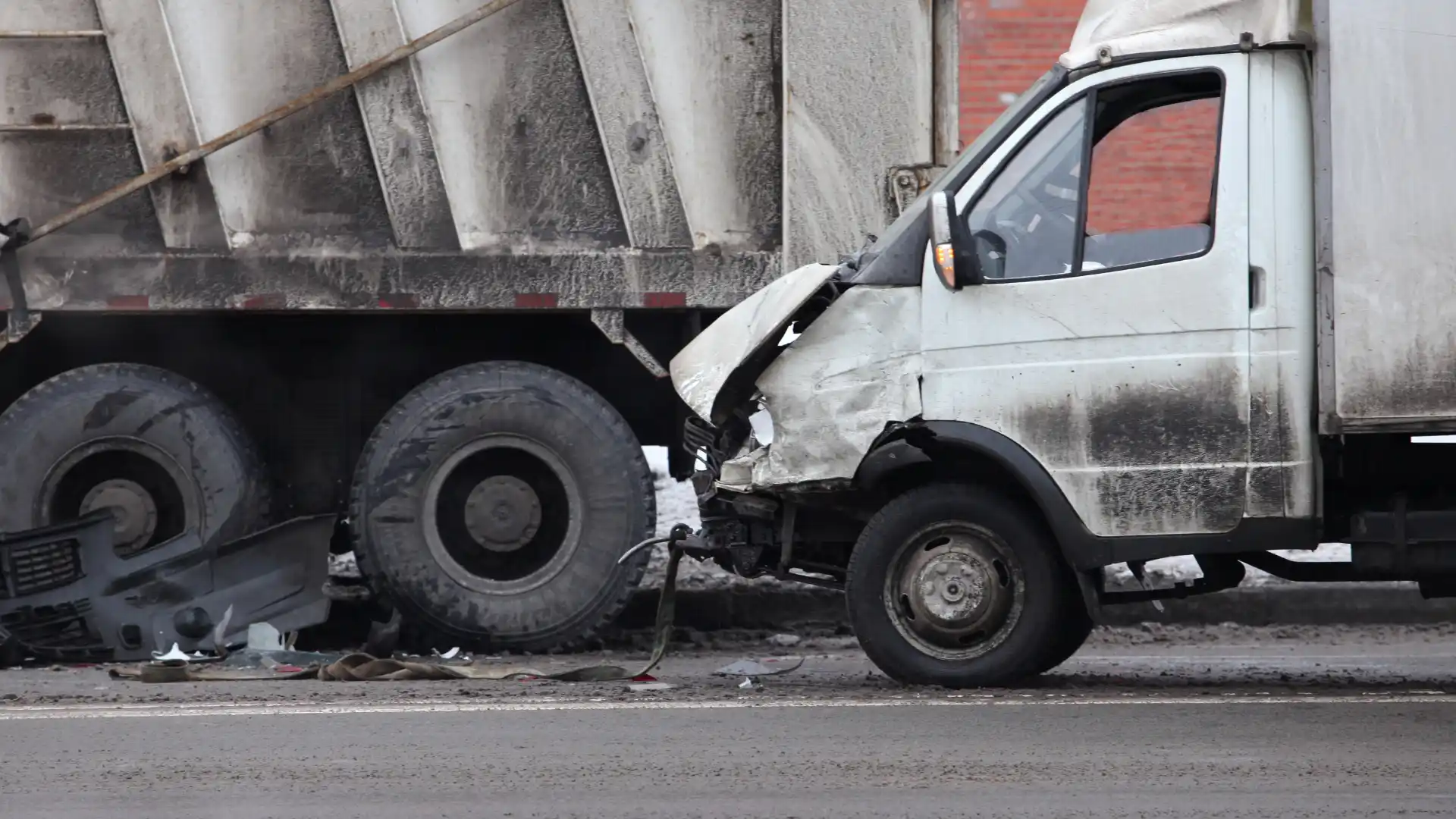 Van with a crushed front end after rear-ending a large industrial truck on the road.